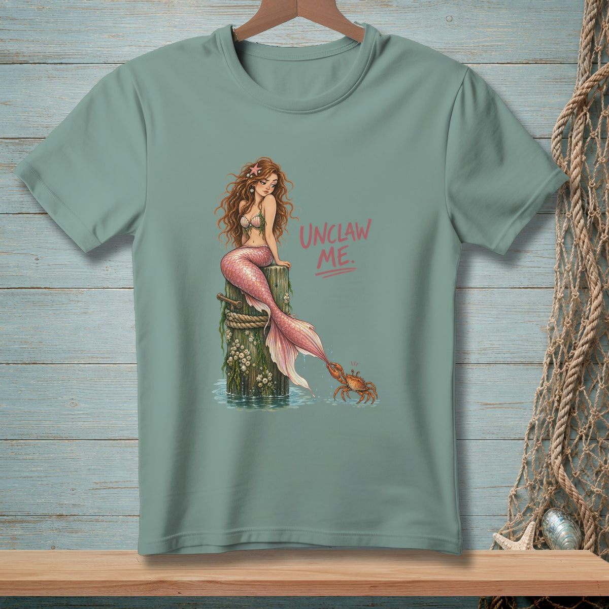 Mermaid with pink tail and text "UNCLAW ME." interacting with a crab.