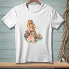 White t-shirt with illustration of a mermaid on rocks with a crab and seashells.