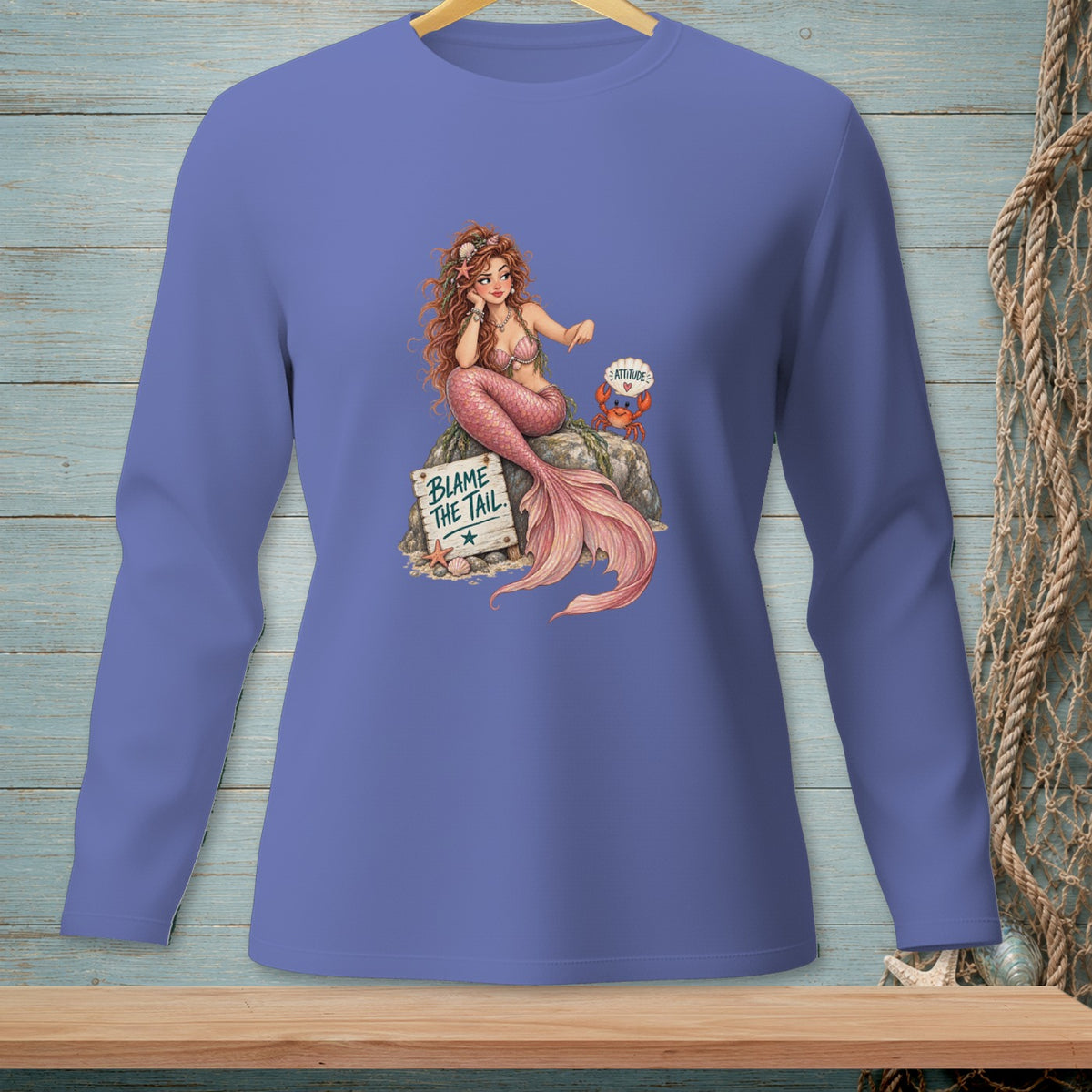 Long sleeve shirt with a mermaid sitting on a rock, with text "Blame the tail".