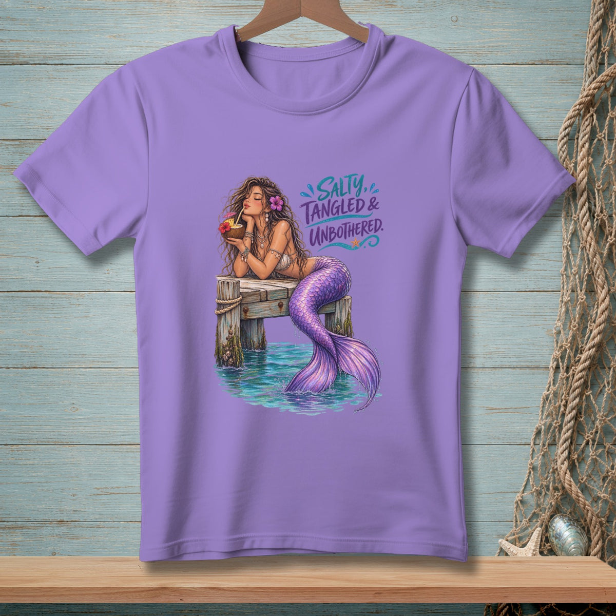 Lavender t-shirt with a mermaid on a dock, drinking from a coconut. "Salty, Tangled & Unbothered."