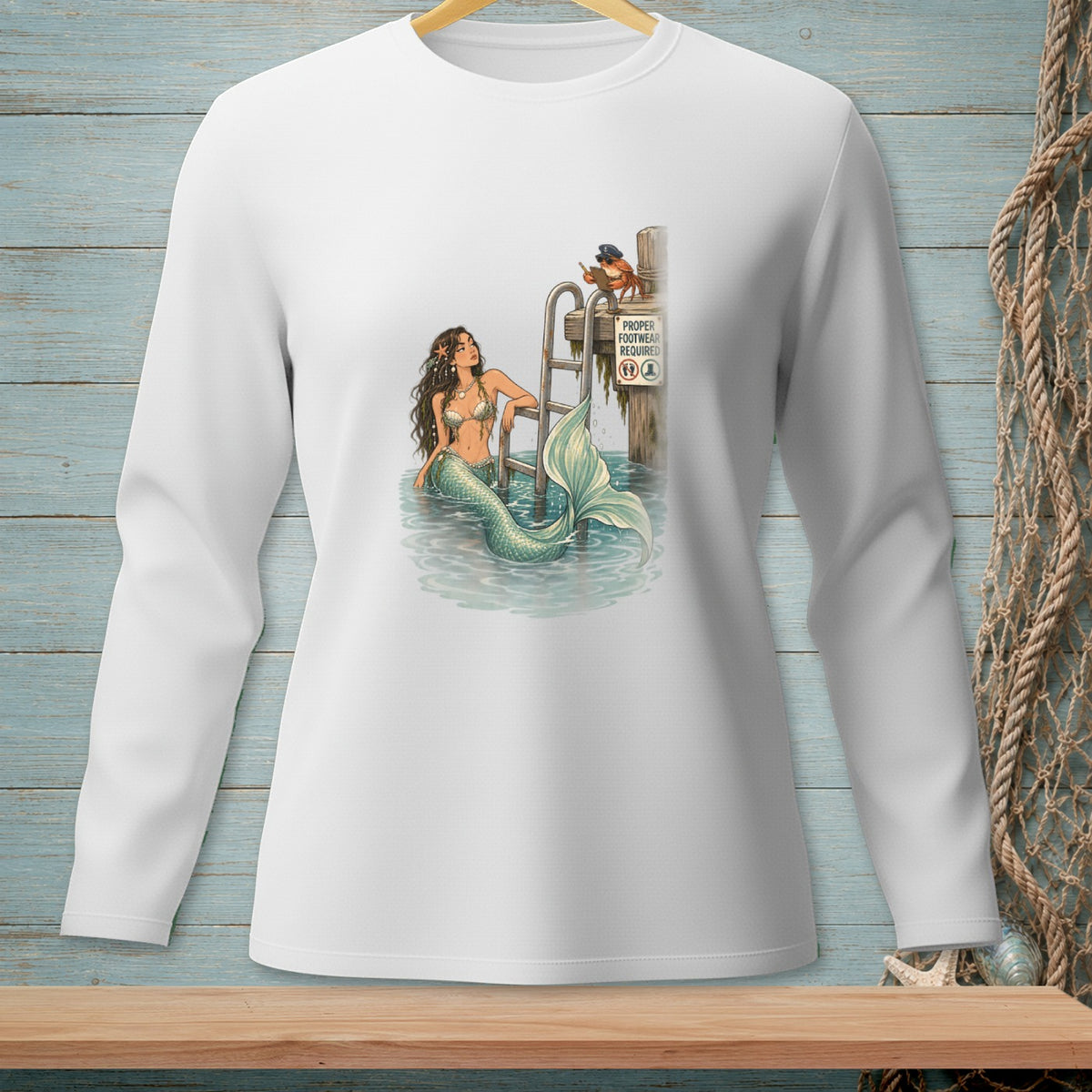 Long sleeve shirt with mermaid illustration and a crab by a pier sign.