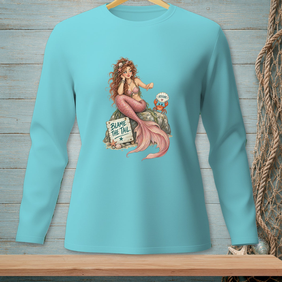 Turquoise long-sleeve shirt with mermaid graphic that reads "Blame the Tail."