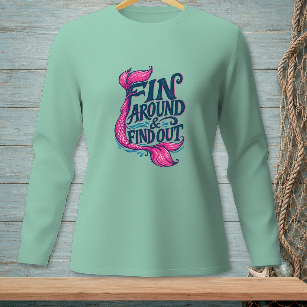 Light green long sleeve shirt with mermaid tail graphic and text "Fin Around & Find Out".