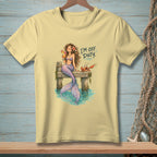 Yellow t-shirt with illustration of a mermaid on a dock, holding a drink, with a crab. Text reads "I'M OFF DUTY."