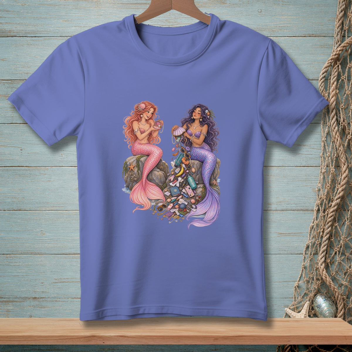 Two mermaids sit on rocks, one with pink tail, the other with purple, surrounded by seashells and jewelry.