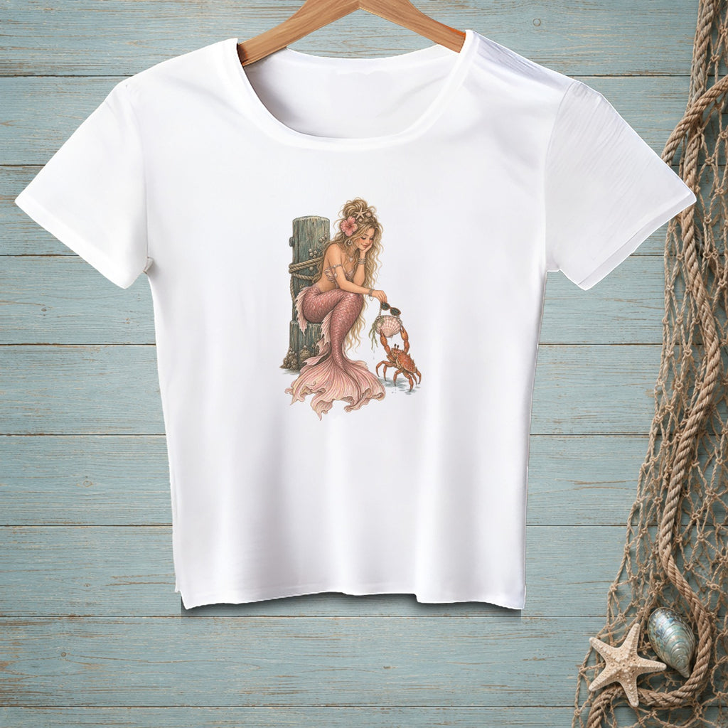 White t-shirt featuring a blonde mermaid interacting with a crab.