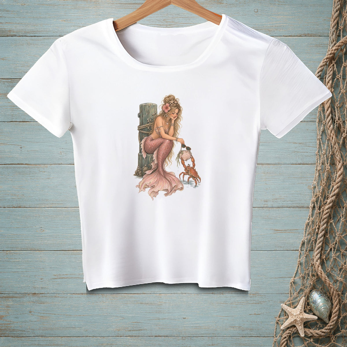 White t-shirt featuring a blonde mermaid interacting with a crab.