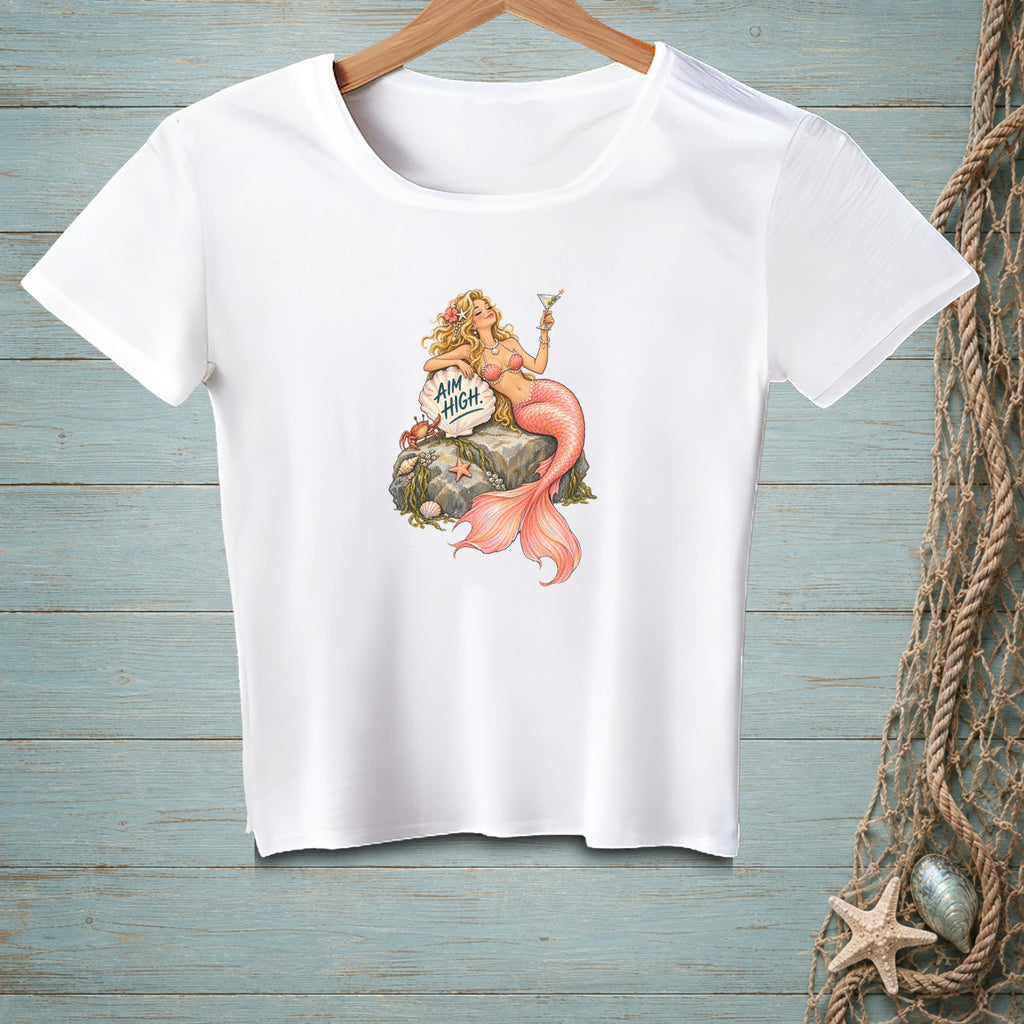 White t-shirt with a mermaid holding a cocktail, sitting on a rock with text.