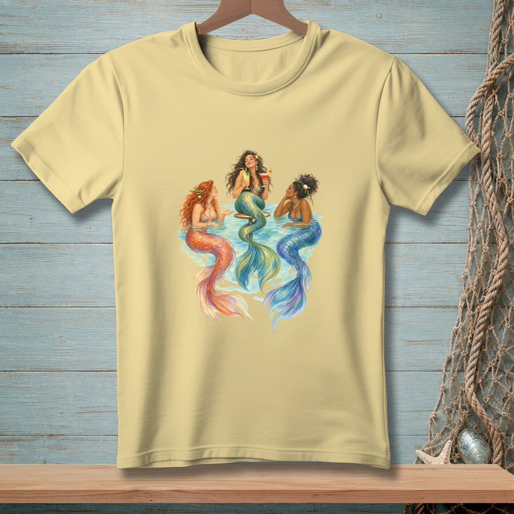Three mermaids with colorful tails sit and drink cocktails together.