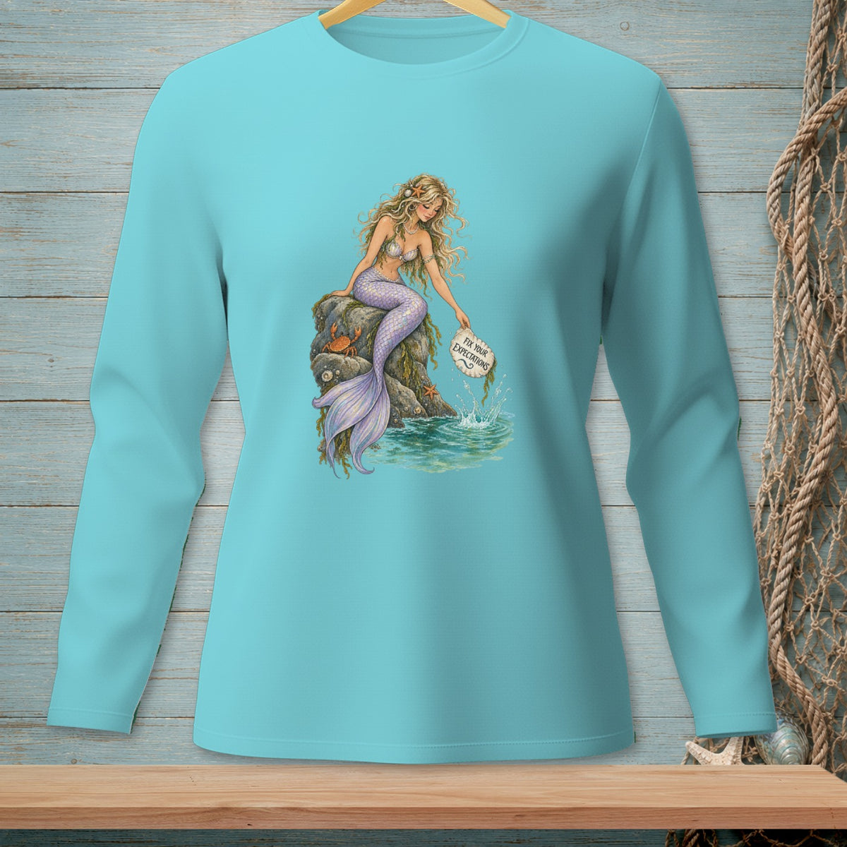 Long-sleeve shirt with a mermaid sitting on a rock, holding a sign that reads "Fix Your Expectations."