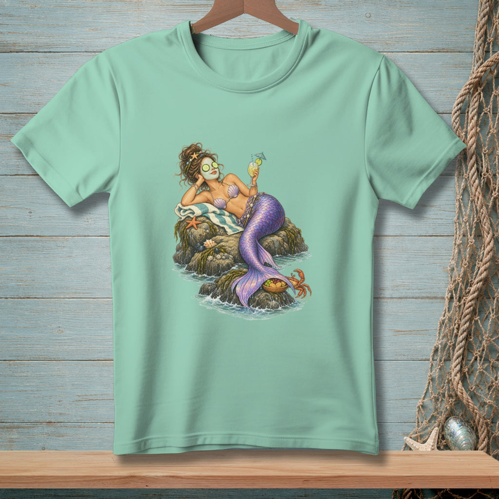 Mermaid relaxing on rocks with a drink, wearing eye patches and a seashell bikini.
