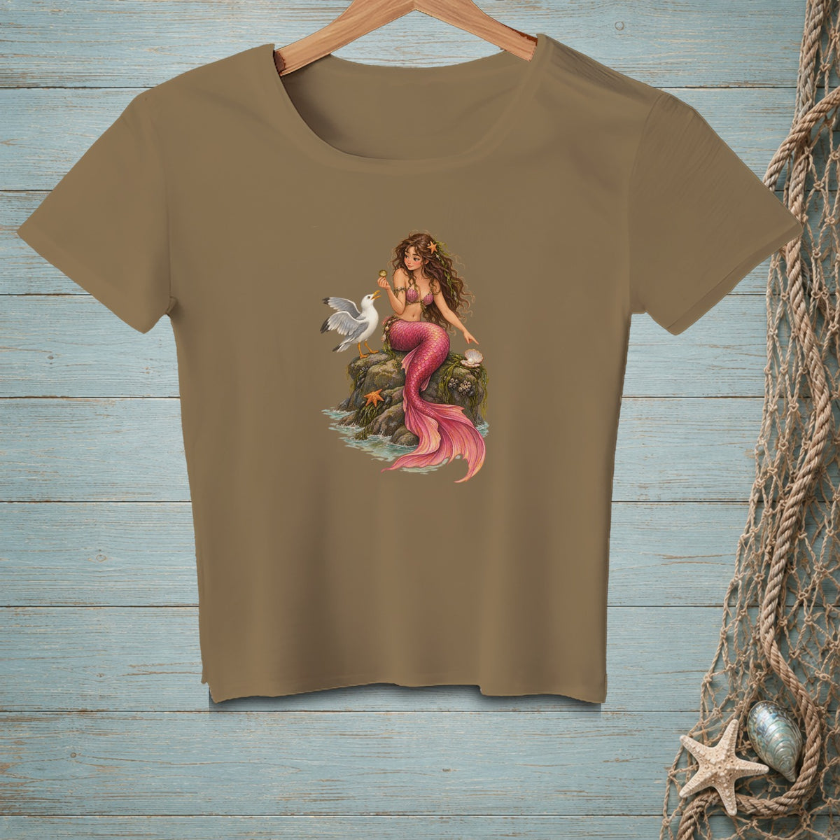 Brown t-shirt with a graphic of a mermaid sitting on a rock with a seagull.