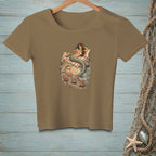 T-shirt graphic of a mermaid reading on a rock with crabs on a beach.
