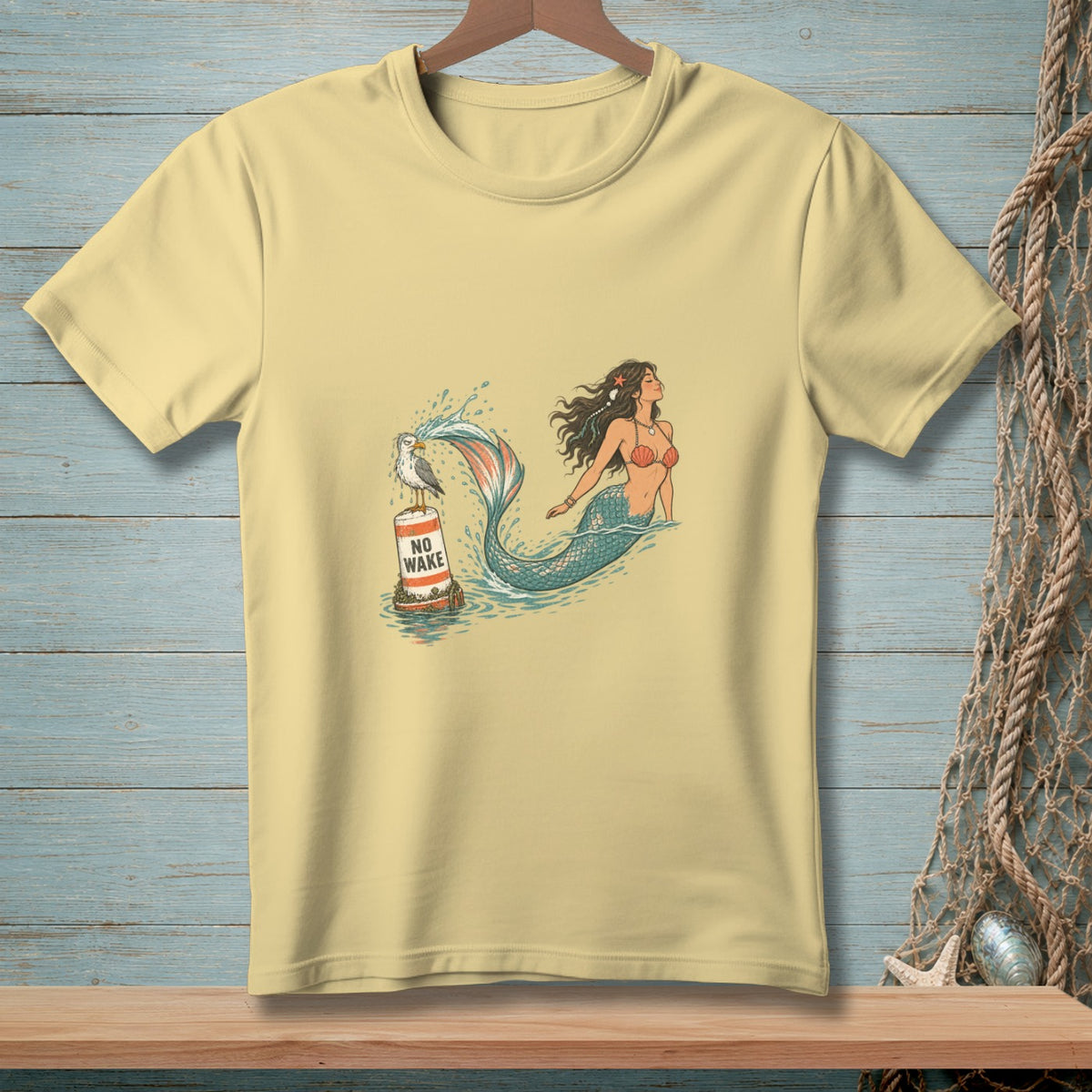 Pale yellow t-shirt with a mermaid and seagull on a buoy with "NO WAKE" text.
