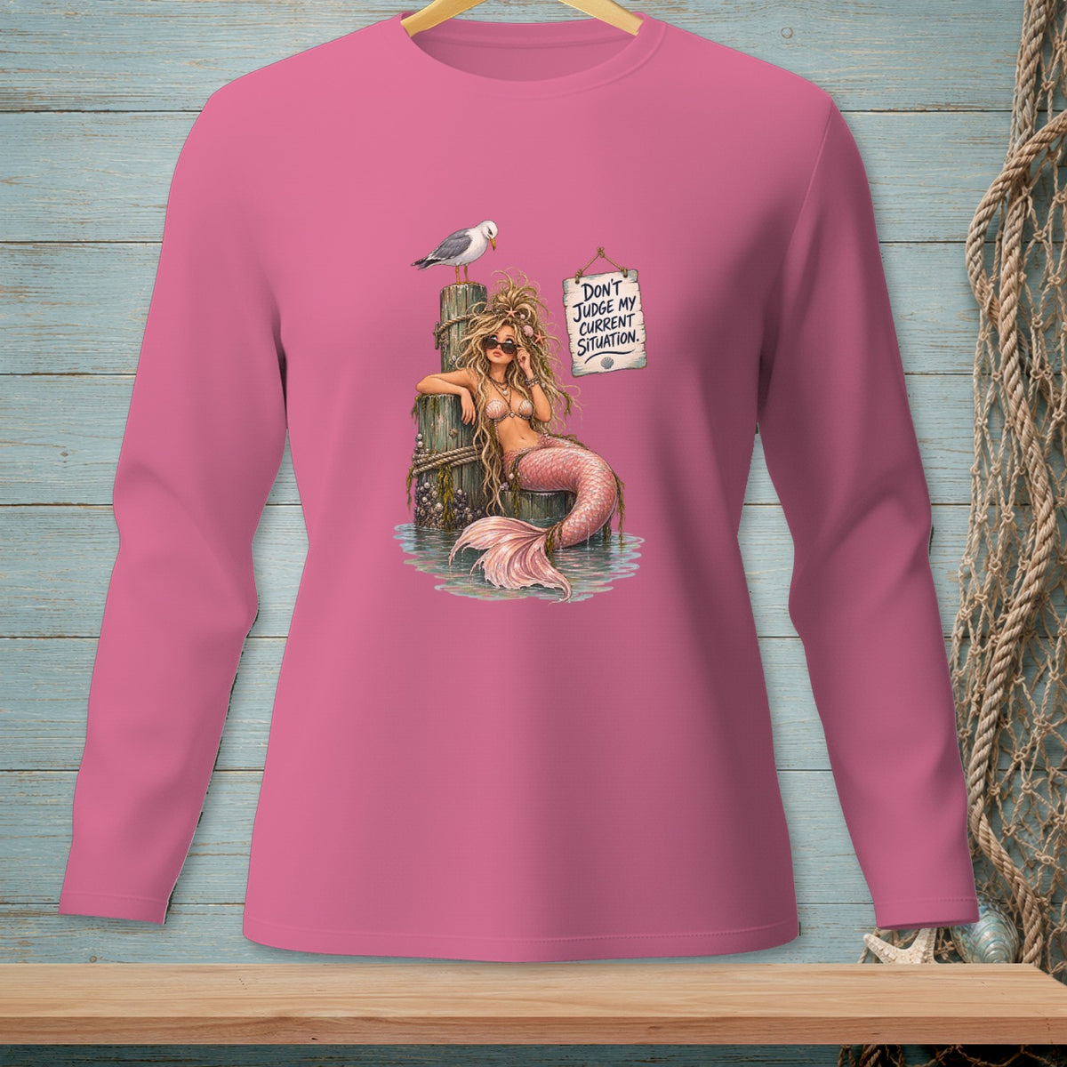 Pink long sleeve shirt with a mermaid, seagull, and text: "Don't judge my current situation."