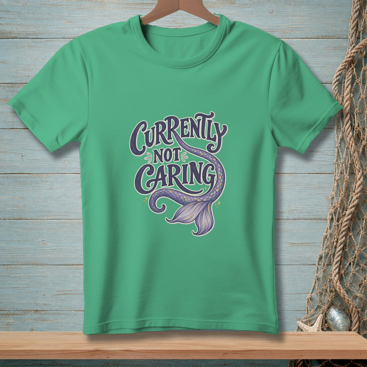 Green t-shirt with text "Currently Not Caring" and a purple mermaid tail.