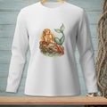 Long-sleeve white t-shirt with mermaid, lobster, and chocolates graphic on rock by water.