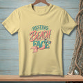 Yellow t-shirt with "Resting Beach Face" graphic and mermaid tail.