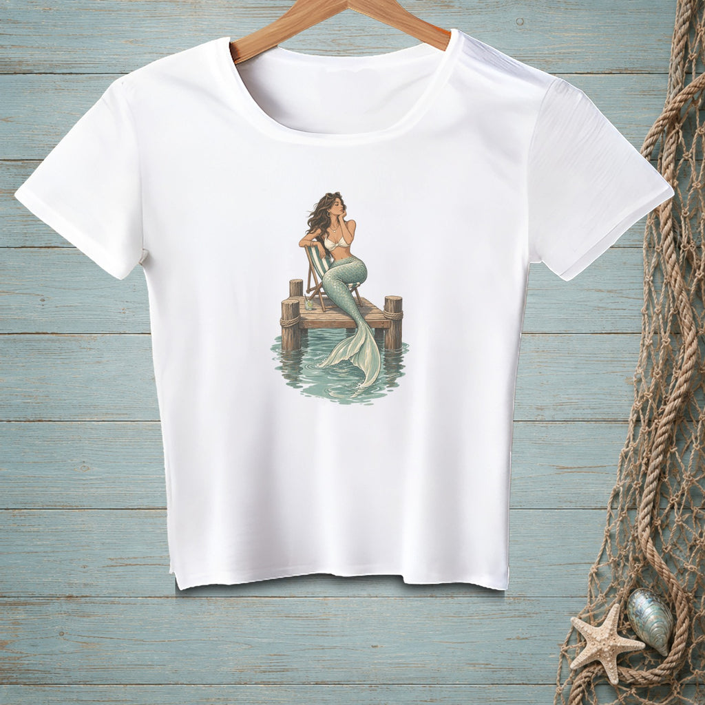 White t-shirt with a graphic of a mermaid sitting on a dock.