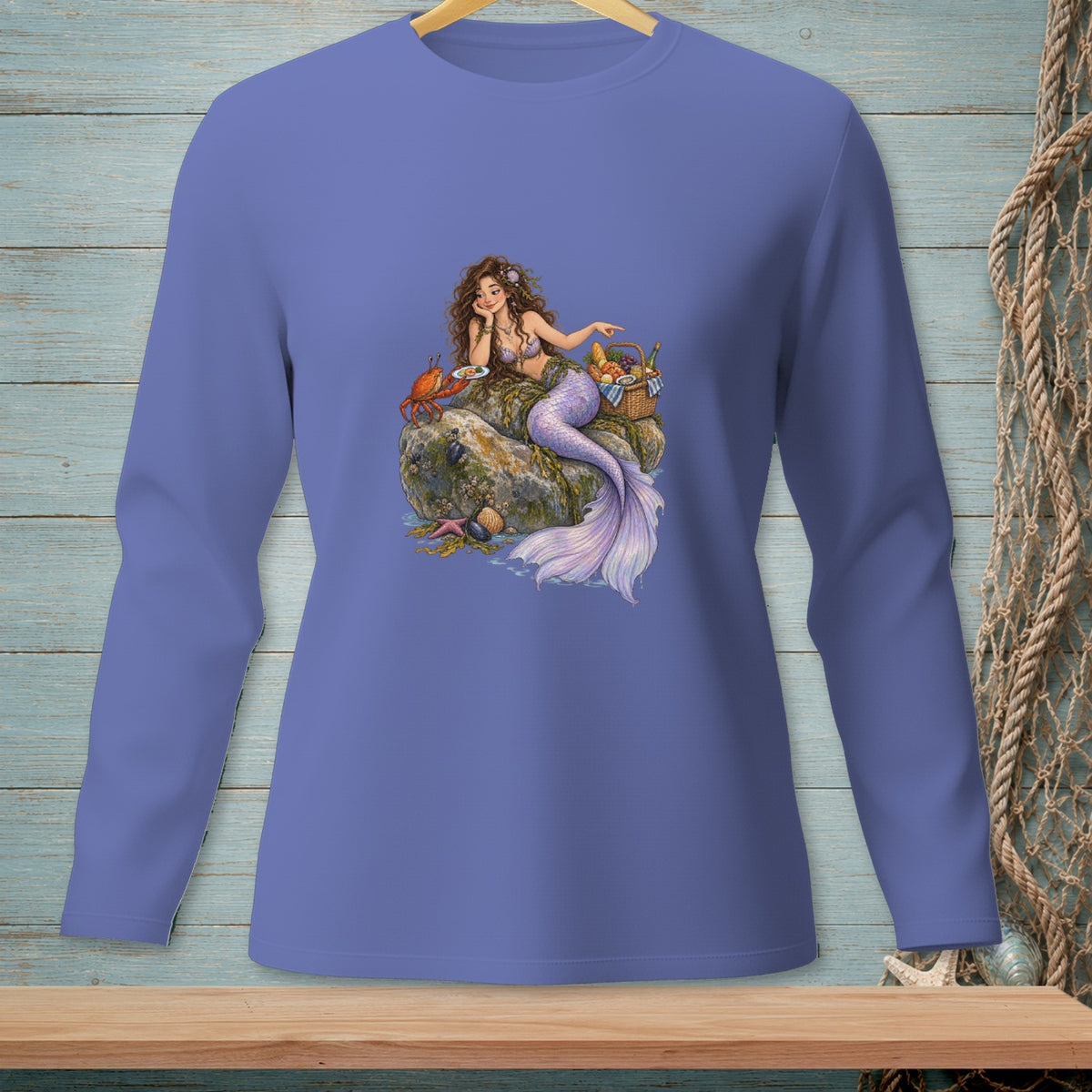 Mermaid with a crab and picnic basket on rocks, printed on a purple long-sleeve shirt.