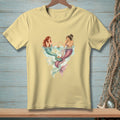 Two mermaids with colorful tails sit at a table in water, serving cake.