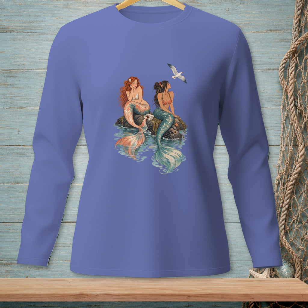 Two mermaids sit on rocks with a seagull flying overhead.