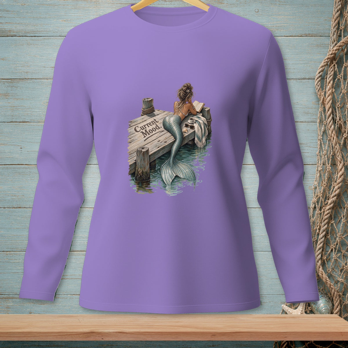 Lavender long-sleeve shirt with a mermaid reading on a dock, with text "Current Mood."