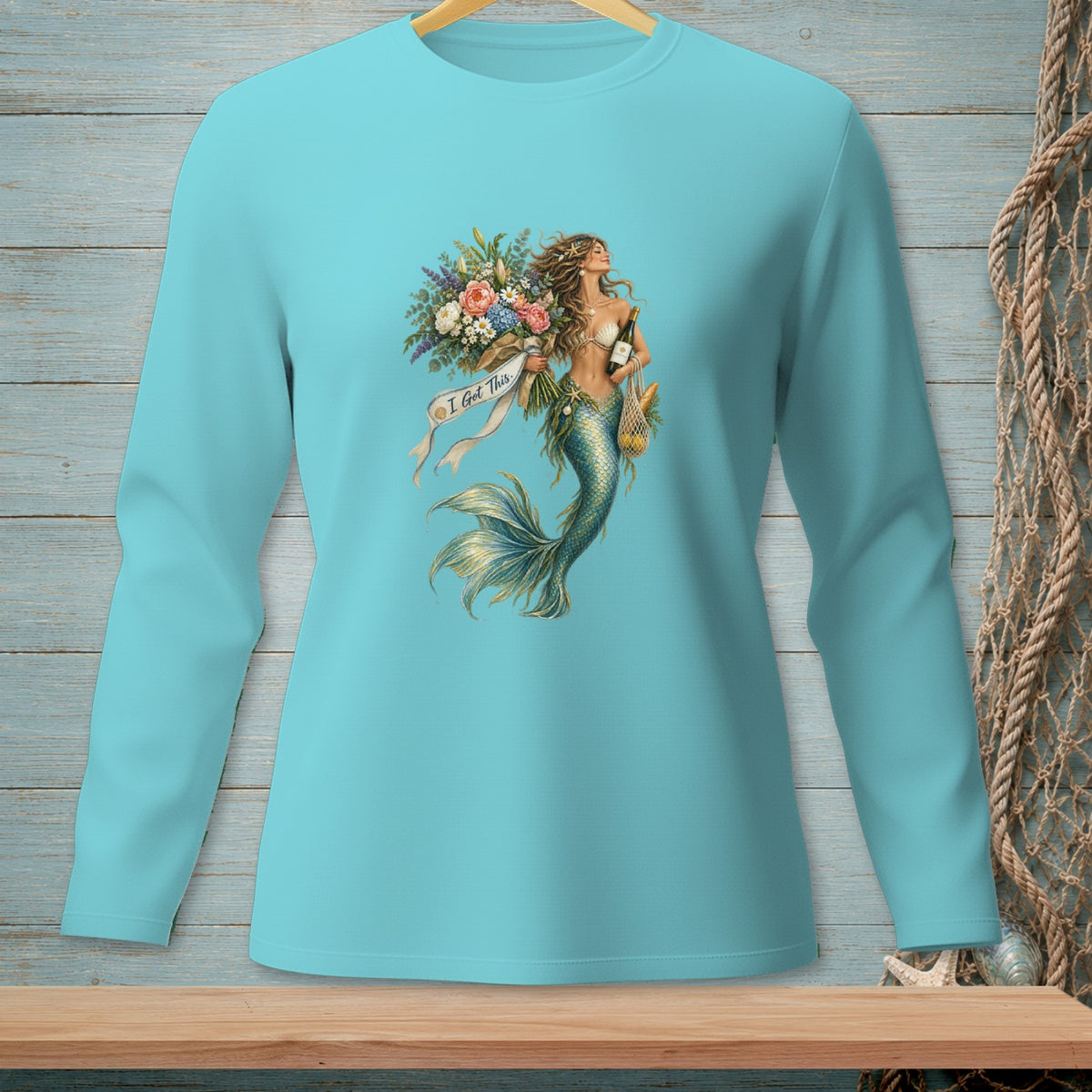 Teal long-sleeve shirt with mermaid graphic holding flowers, wine, and a net bag with bread.
