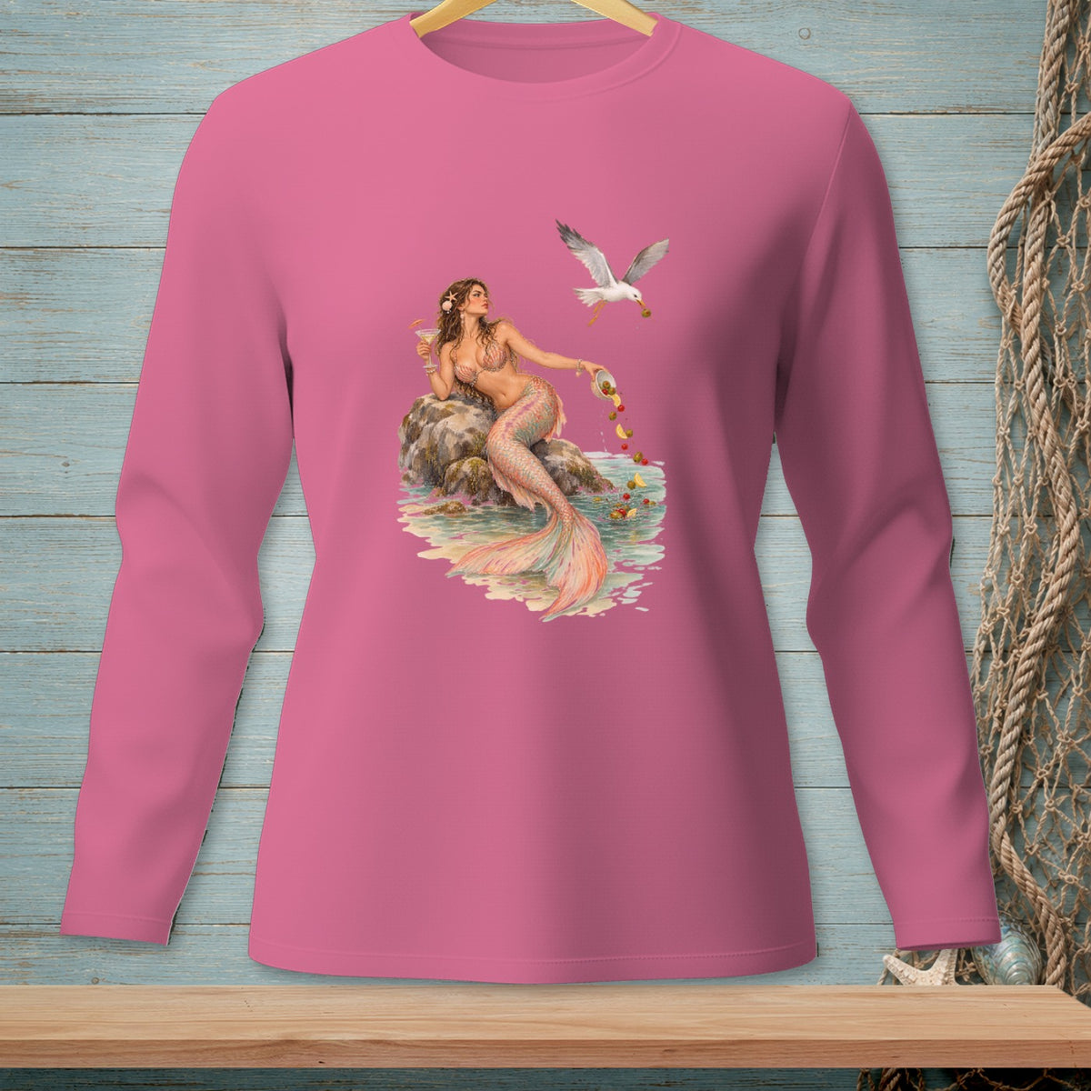 Long sleeve pink shirt with a mermaid sitting on a rock feeding a seagull.