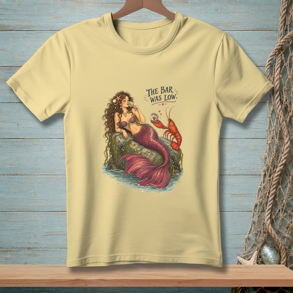 Mermaid with lobster and text "THE BAR WAS LOW" on a pale yellow t-shirt.