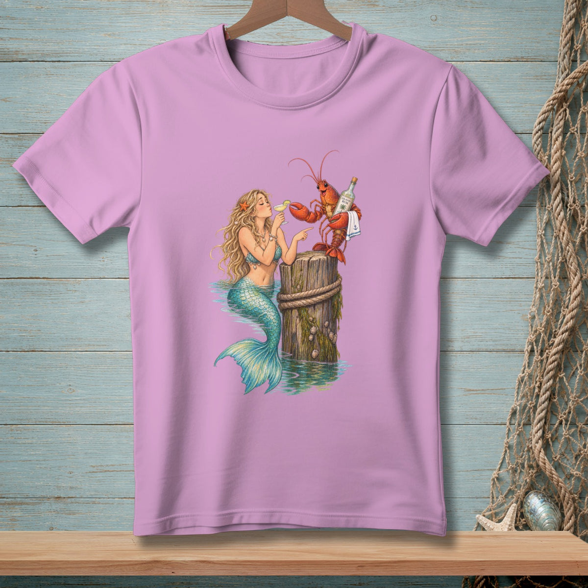 Mermaid and lobster holding drinks on a wooden post artwork on a pink t-shirt.