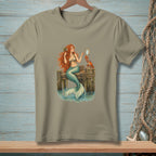Mermaid with red hair sitting on a dock, holding a mirror, with a crab.