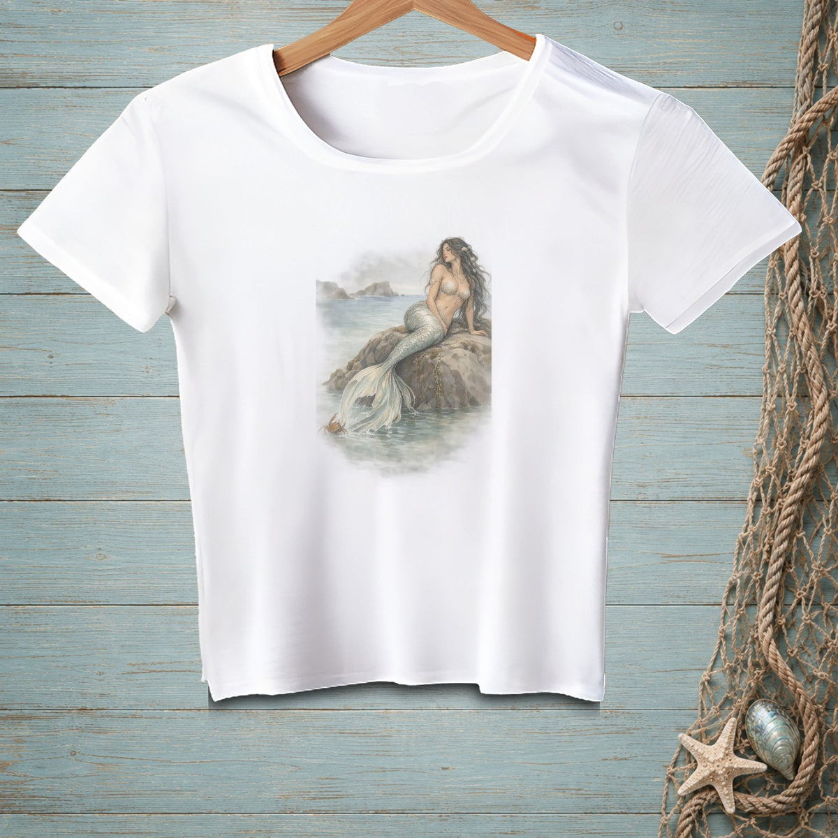 White t-shirt with a watercolor-style print of a mermaid sitting on a rock.