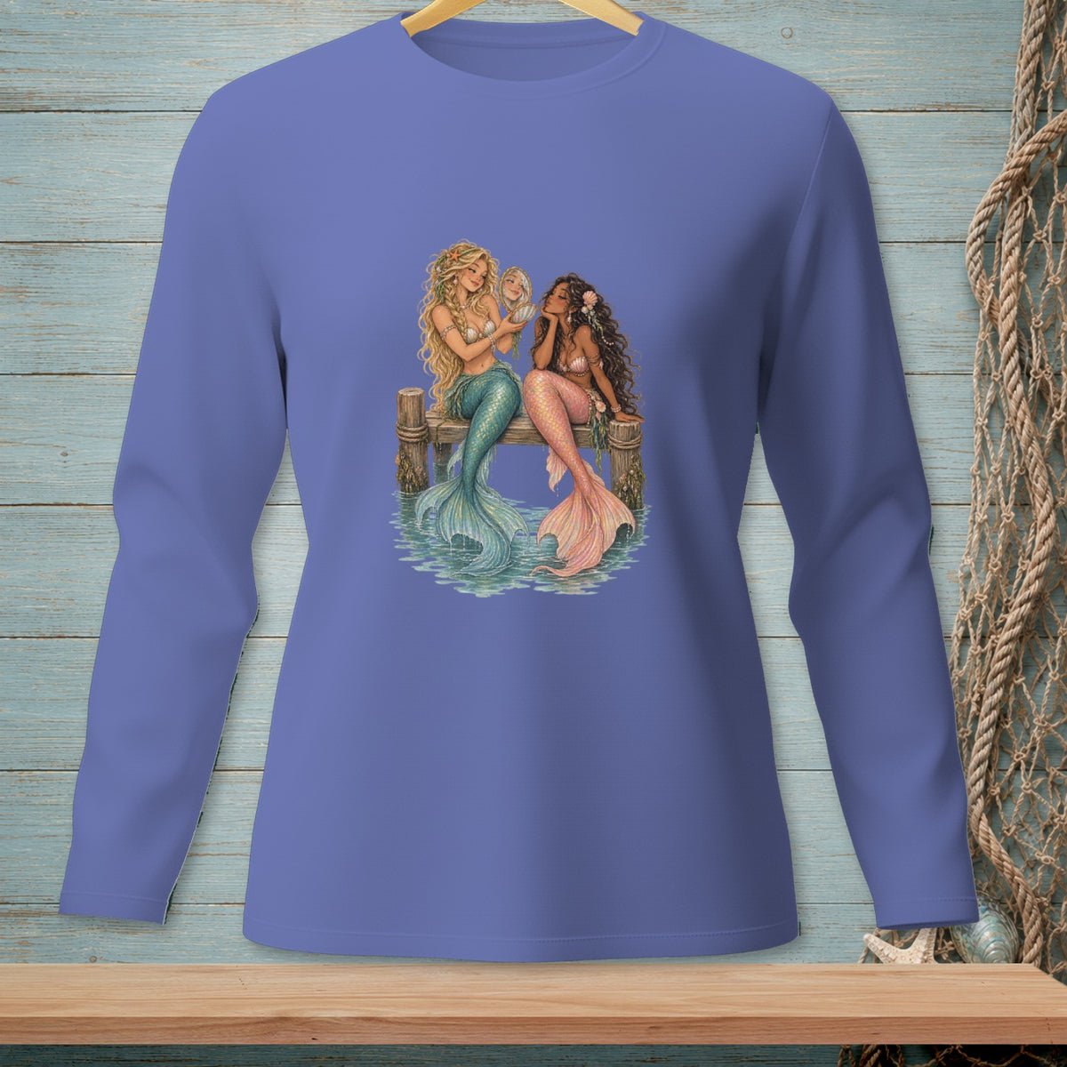 Two mermaids with colorful tails sit on a wooden dock looking at a shell.