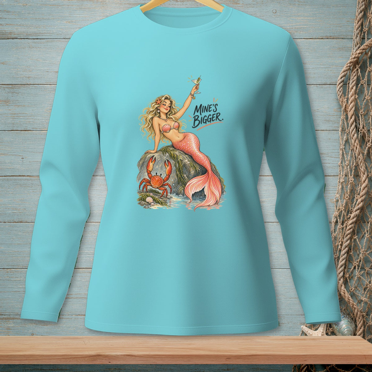 Aqua long-sleeve shirt with graphic of a mermaid and crab, and text "Mine's Bigger."