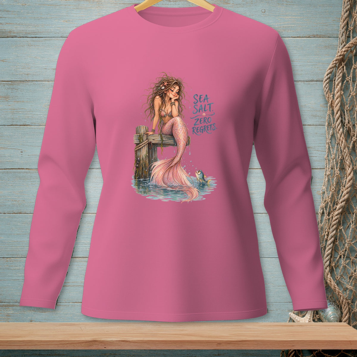 Pink long-sleeve shirt with mermaid graphic and text "SEA SALT ZERO REGRETS."