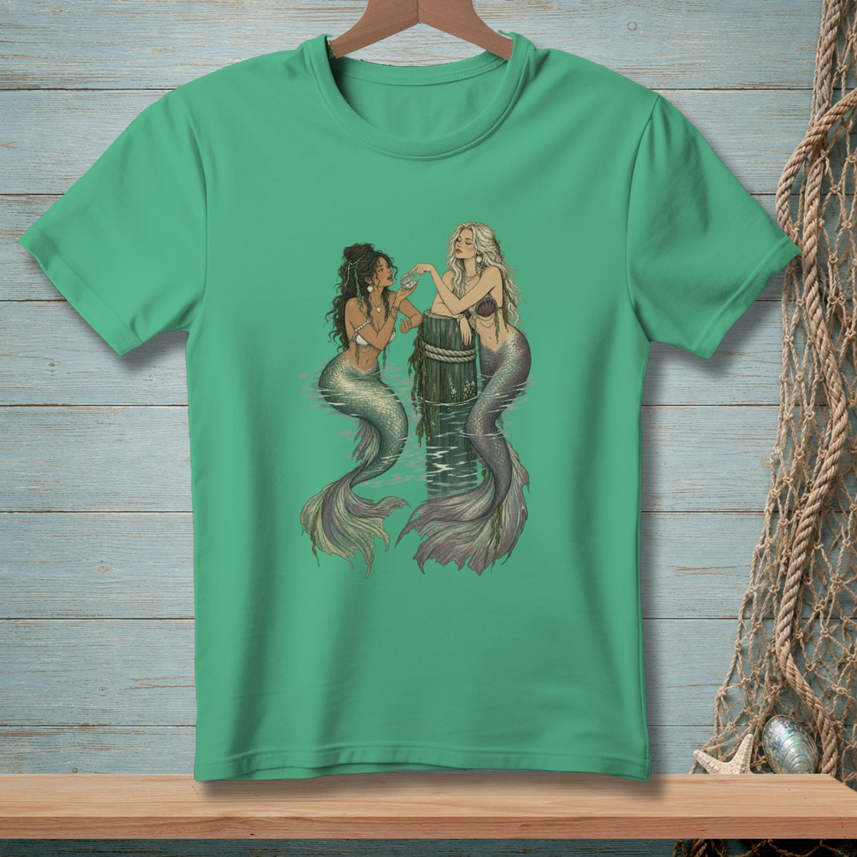 Two mermaids sitting in water next to a wooden post, with one holding a shell.