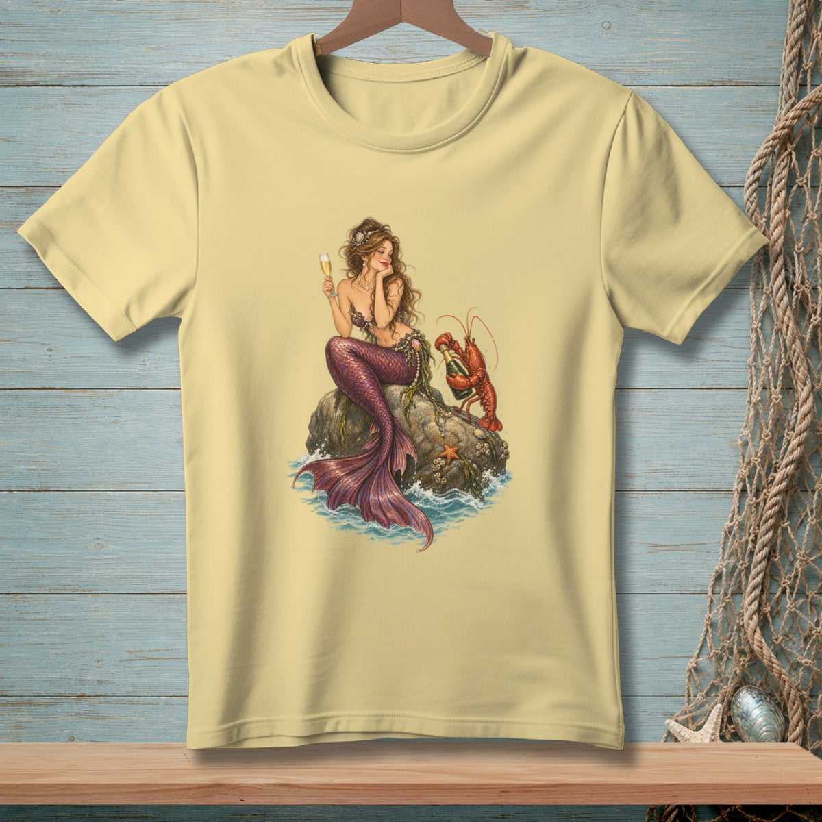 Pale yellow t-shirt featuring a mermaid holding a champagne glass with a lobster.