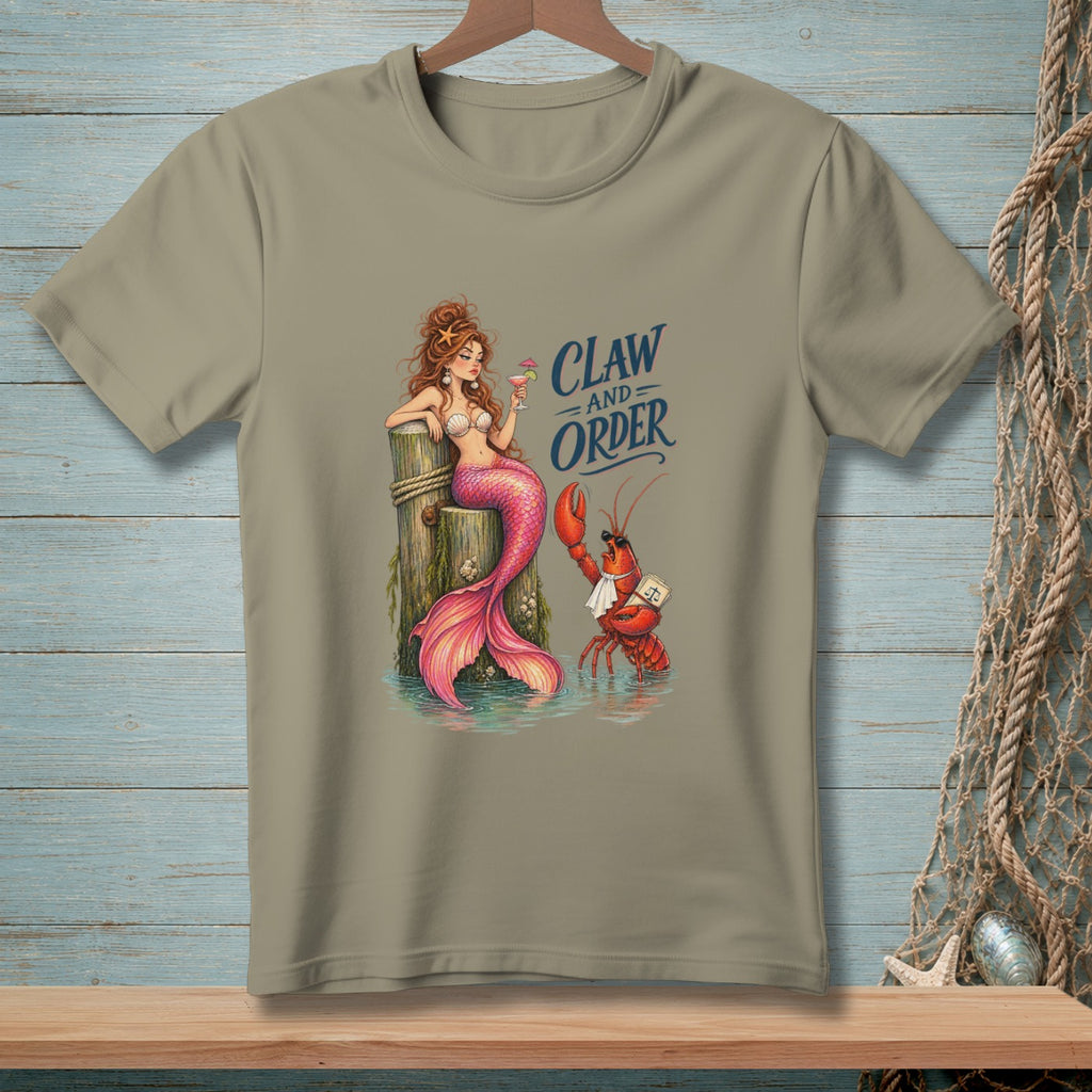 Mermaid and lobster with text "Claw and Order" graphic on a tan t-shirt.
