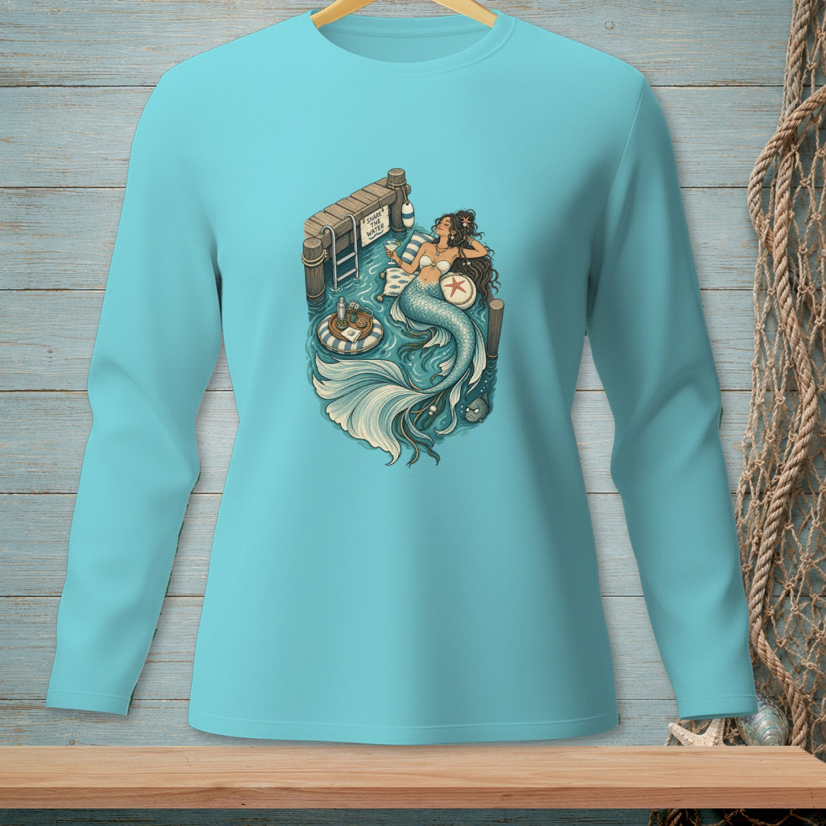 Mermaid relaxing by dock with "Share the Water" sign, on light blue long-sleeve shirt.