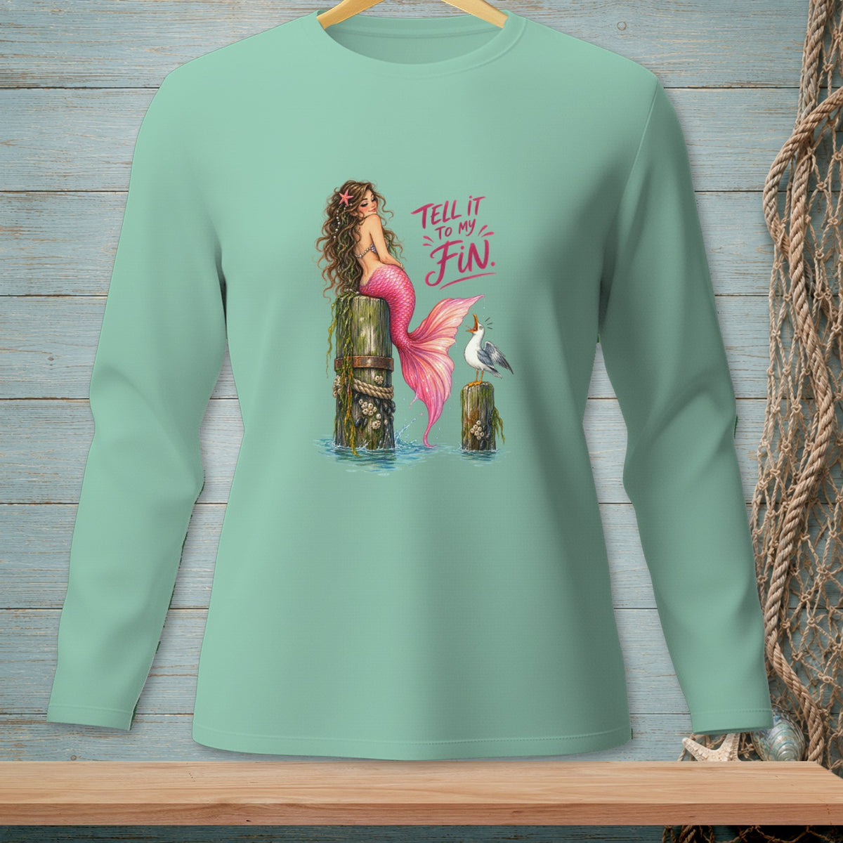 Mermaid with pink tail sitting on a post with text "Tell it to my fin".