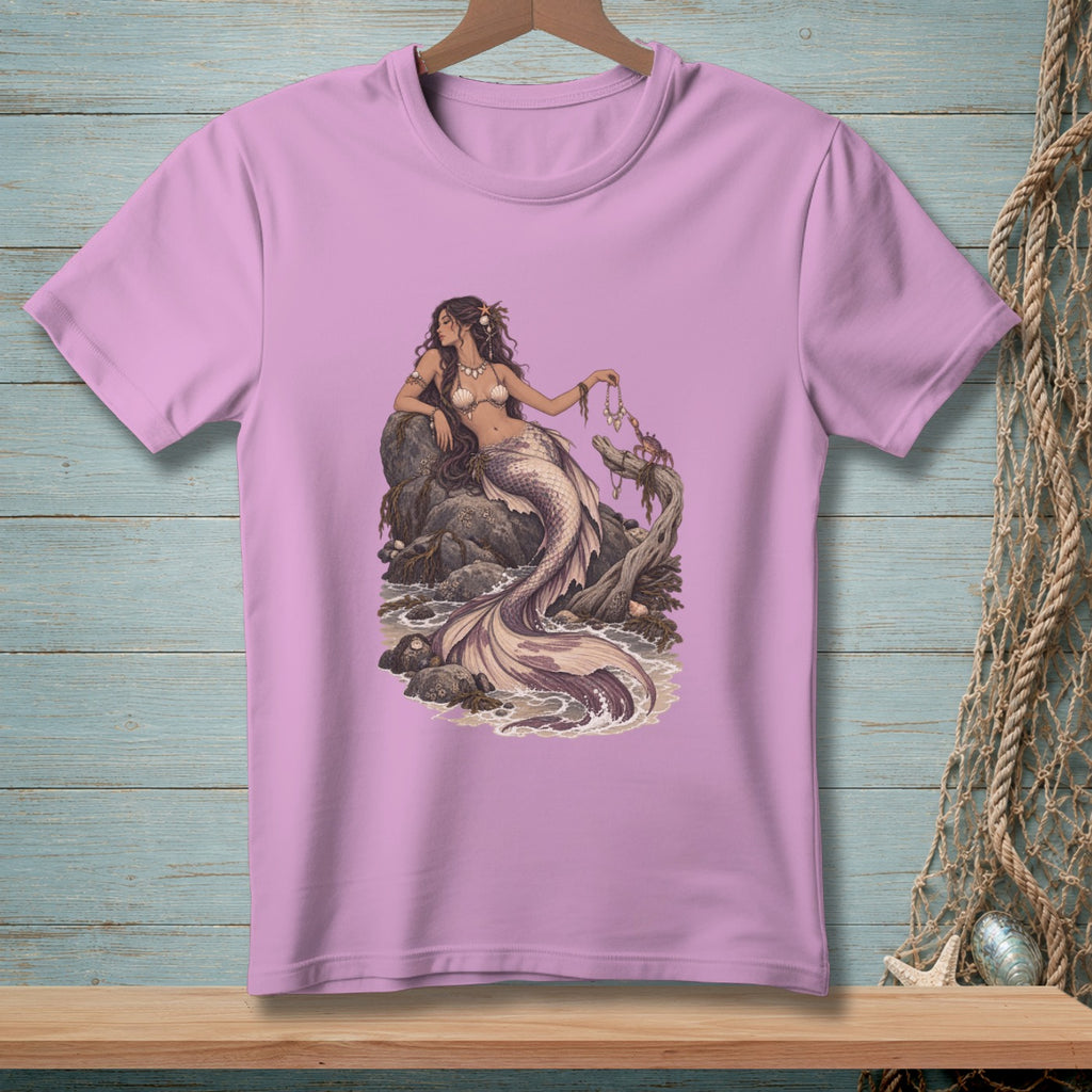 Pink t-shirt with a detailed illustration of a mermaid and a crab on rocks by the sea.