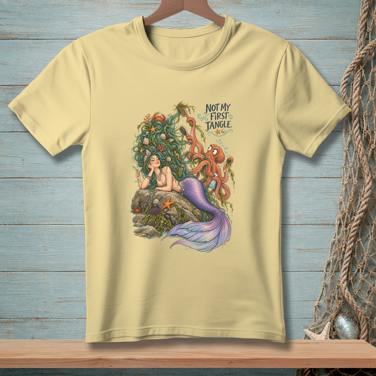 Light yellow t-shirt with mermaid and octopus artwork, text "Not My First Tangle."