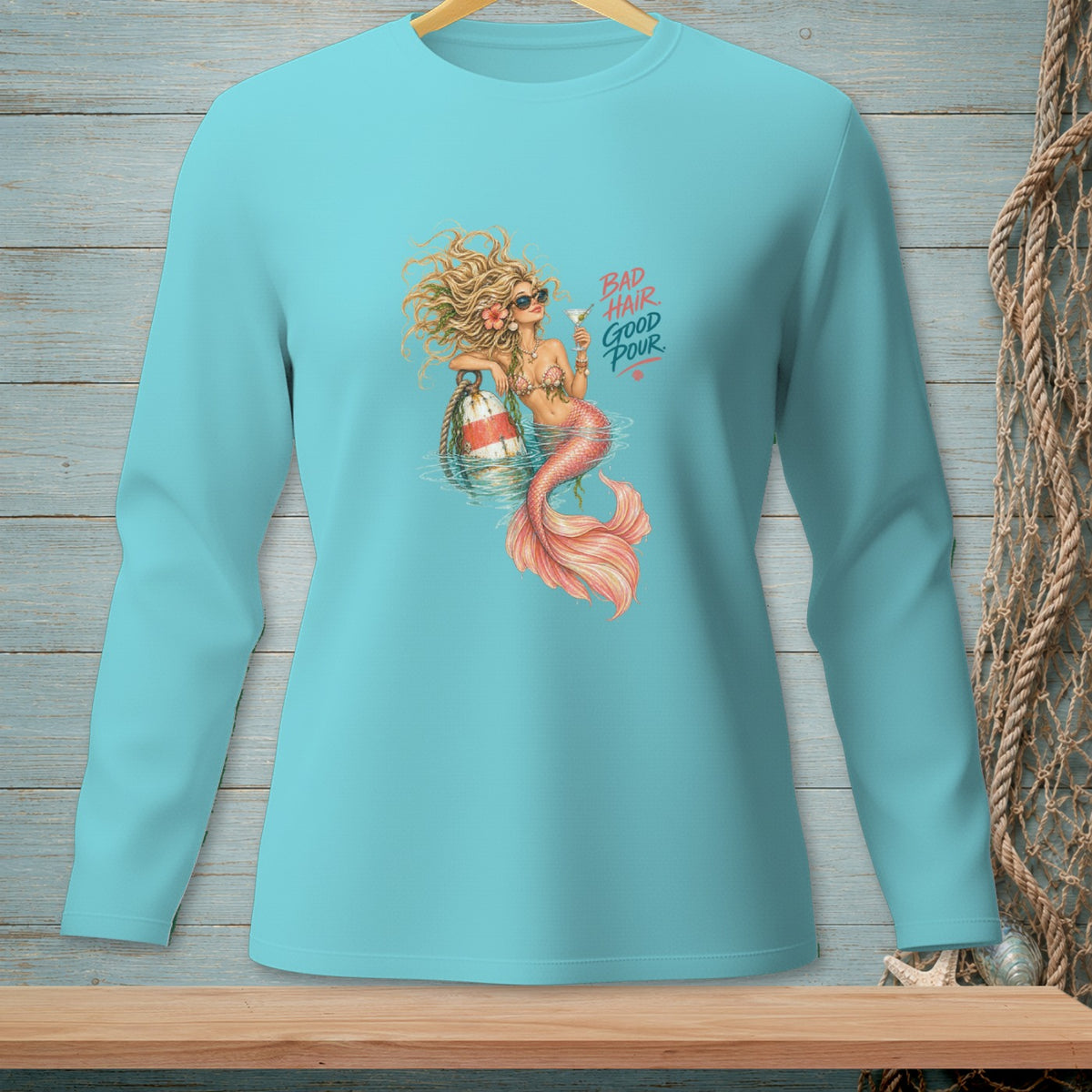 Teal long-sleeve shirt with a mermaid graphic holding a drink and text that reads "BAD HAIR GOOD POUR."