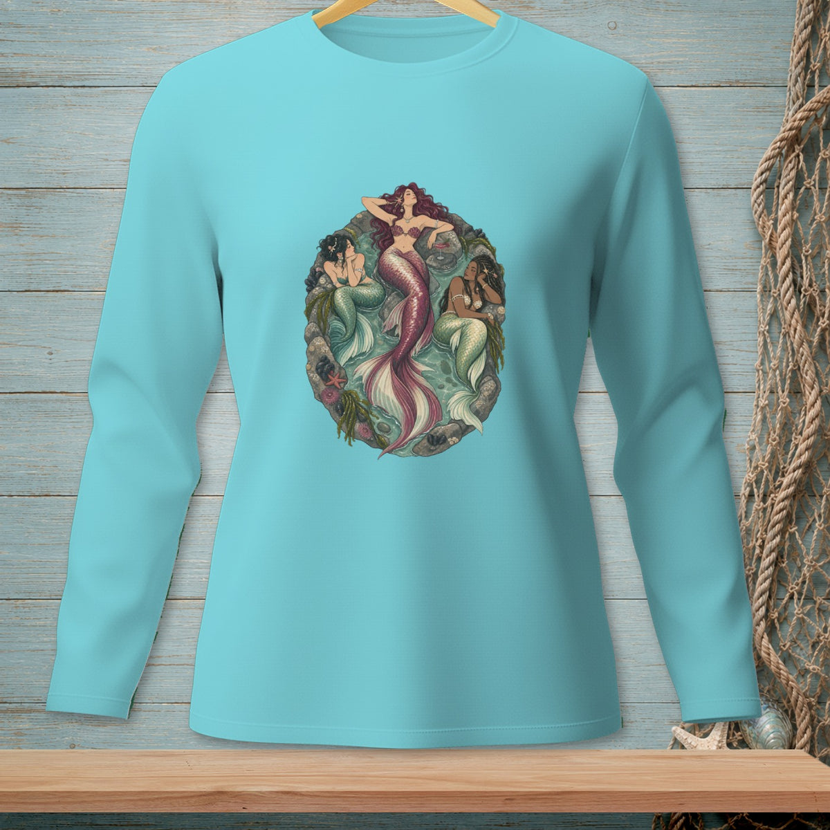 Teal long-sleeve shirt with an oval graphic of three mermaids and sea life.