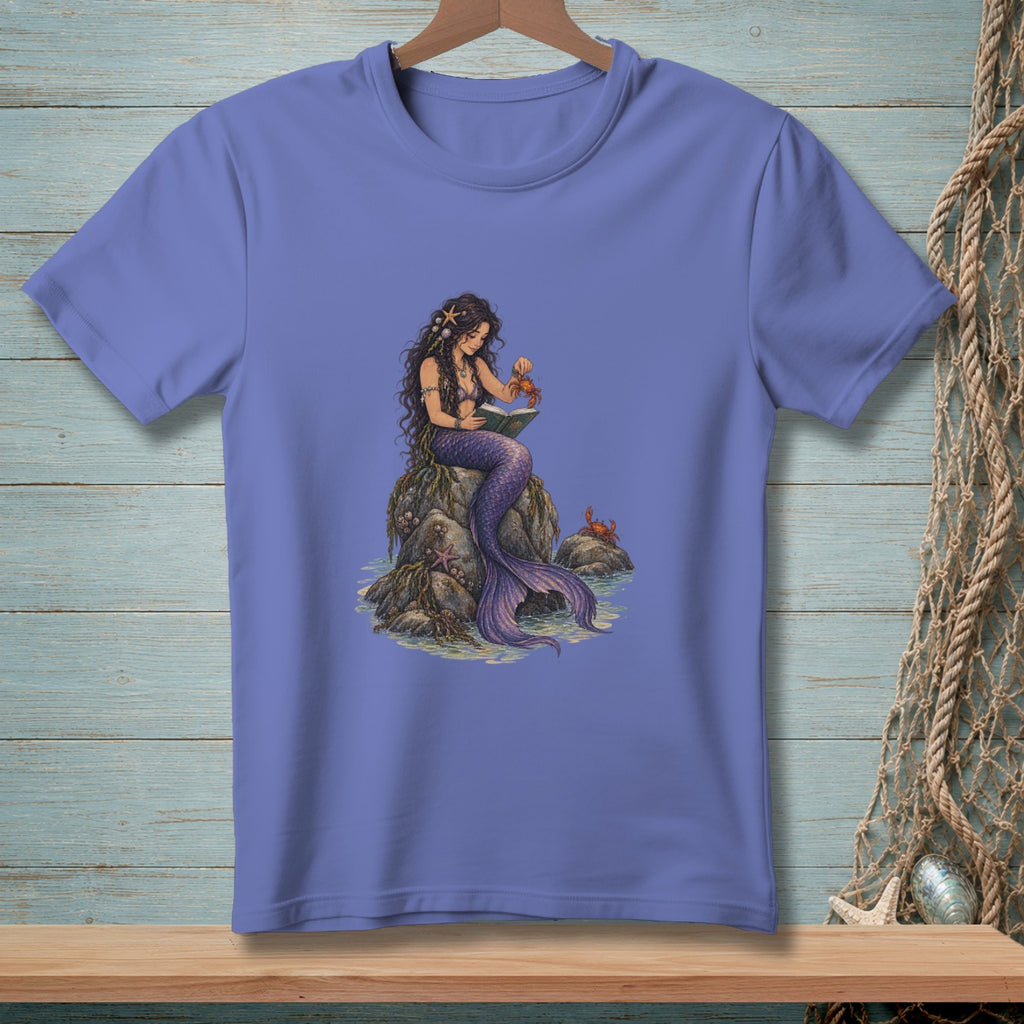 Mermaid sitting on rocks reading a book to a crab, with ocean and other crabs nearby.