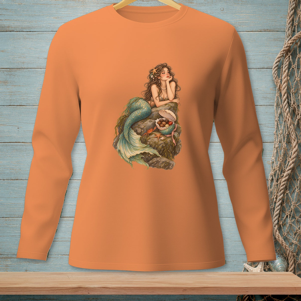 Long-sleeve orange t-shirt with a mermaid graphic on a rock.