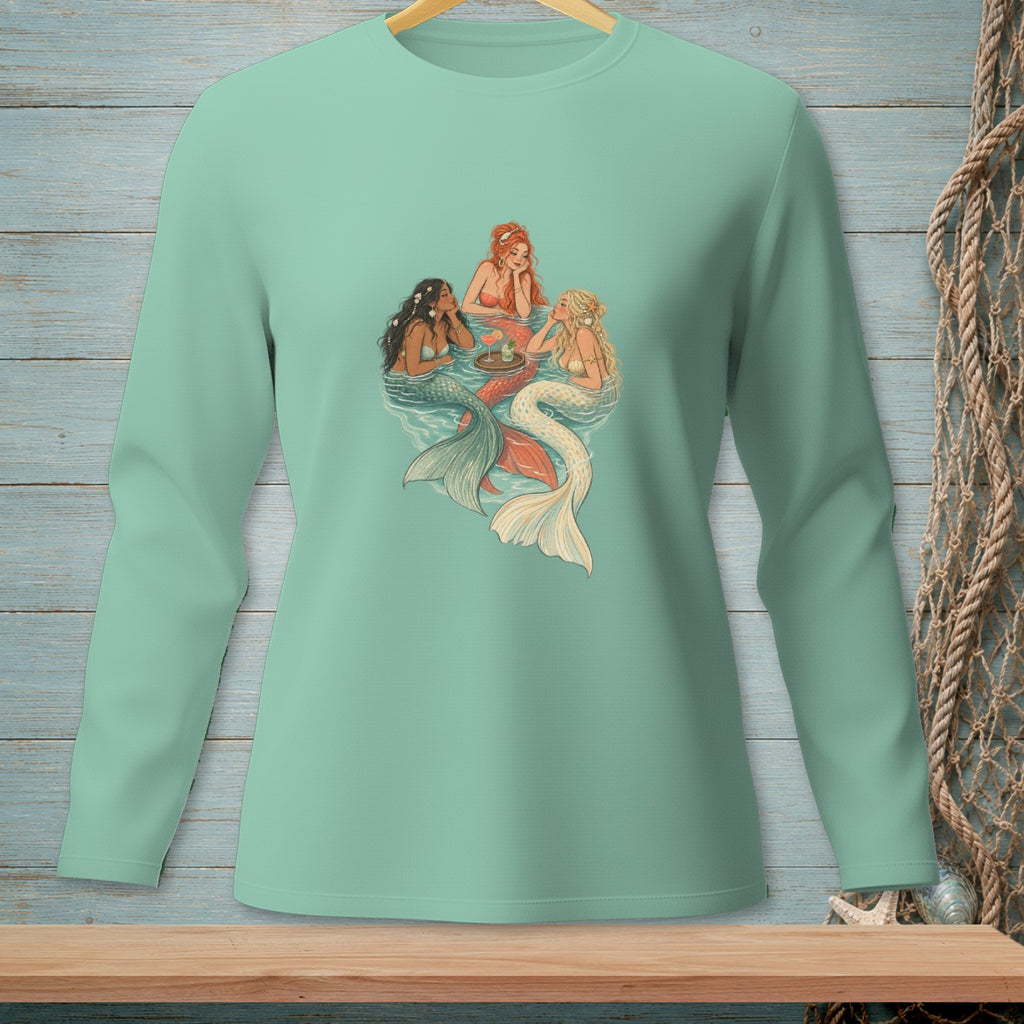 Three mermaids with colorful tails gather around a tray with drinks in the water.