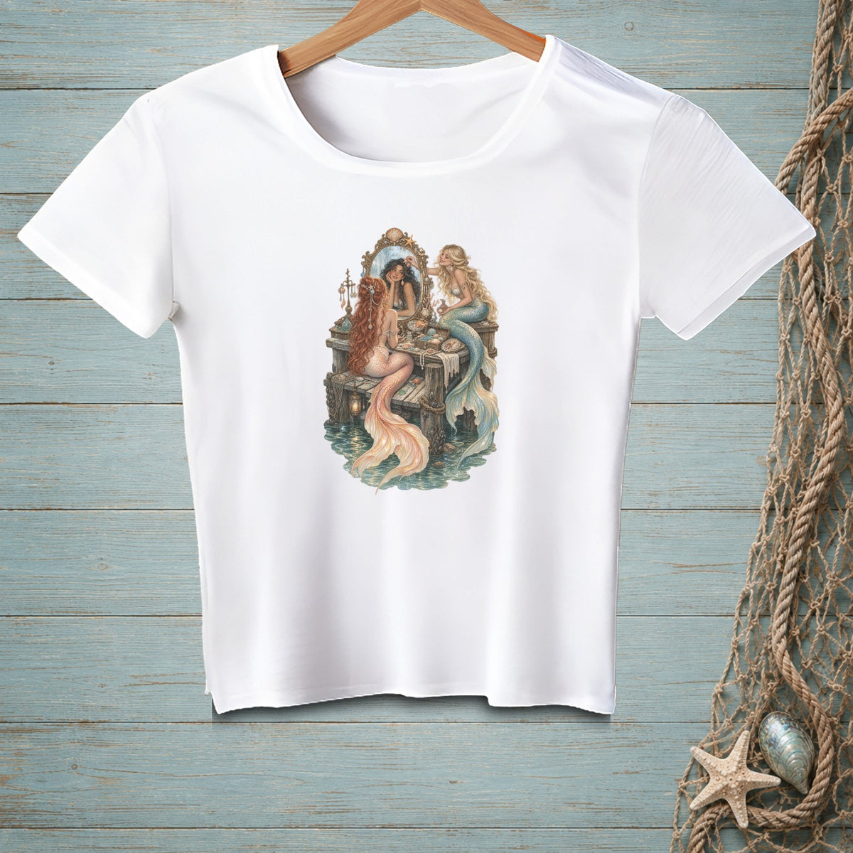 T-shirt with watercolor illustration of two mermaids at a vanity mirror.