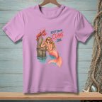Mermaid and lobster graphic with text "Keep Your Claws On" on a pink t-shirt.